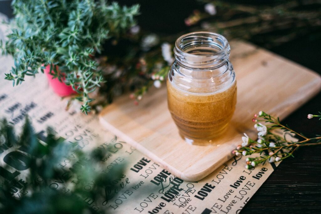shallow focus photography clear glass jar on chopping board, crystallised coconut nectar, organic coconut palm nectar, secret coconut nectar, coconut flower nectar